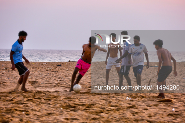 Youth are playing a game of football (soccer) by the ocean at sunset along Paruthiyoor Beach in Paruthiyoor, Kerala, India, on April 15, 202...