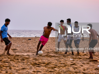 Youth are playing a game of football (soccer) by the ocean at sunset along Paruthiyoor Beach in Paruthiyoor, Kerala, India, on April 15, 202...