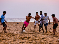 Youth are playing a game of football (soccer) by the ocean at sunset along Paruthiyoor Beach in Paruthiyoor, Kerala, India, on April 15, 202...