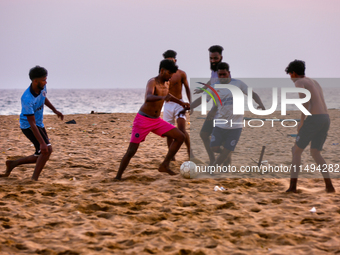 Youth are playing a game of football (soccer) by the ocean at sunset along Paruthiyoor Beach in Paruthiyoor, Kerala, India, on April 15, 202...