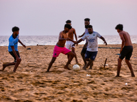 Youth are playing a game of football (soccer) by the ocean at sunset along Paruthiyoor Beach in Paruthiyoor, Kerala, India, on April 15, 202...