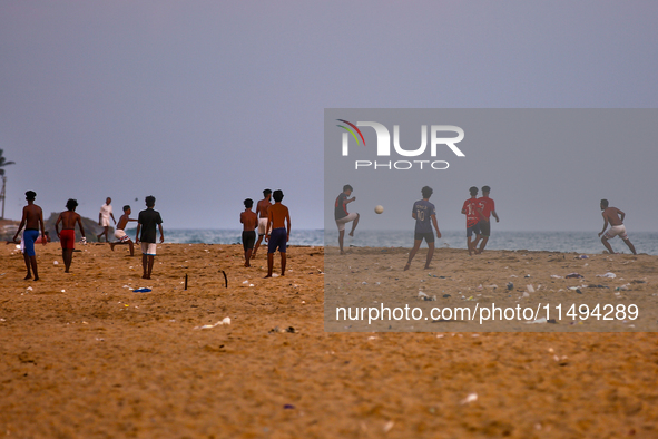 Youth are playing a game of football (soccer) by the ocean at sunset along Paruthiyoor Beach in Paruthiyoor, Kerala, India, on April 15, 202...