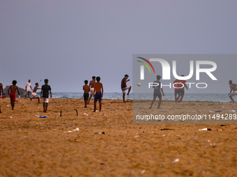 Youth are playing a game of football (soccer) by the ocean at sunset along Paruthiyoor Beach in Paruthiyoor, Kerala, India, on April 15, 202...