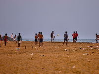 Youth are playing a game of football (soccer) by the ocean at sunset along Paruthiyoor Beach in Paruthiyoor, Kerala, India, on April 15, 202...