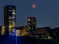 A rare super blue full moon appears rising in the night sky over tall buildings, near the city of Eindhoven in the Netherlands on August 19,...