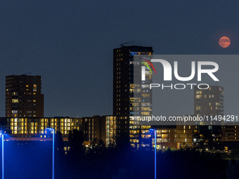 A rare super blue full moon appears rising in the night sky over tall buildings, near the city of Eindhoven in the Netherlands on August 19,...