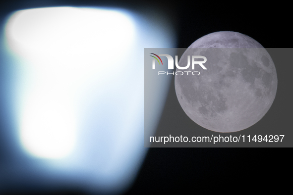 A rare super blue full moon appears rising in the night sky over tall buildings, near the city of Eindhoven in the Netherlands on August 19,...