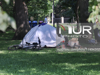 A homeless man is setting up a tent in Queens Park in downtown Toronto, Ontario, Canada, on August 14, 2024. Homelessness is plaguing the ci...