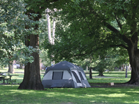 A homeless man is setting up a tent in Queens Park in downtown Toronto, Ontario, Canada, on August 14, 2024. Homelessness is plaguing the ci...