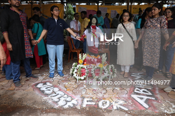 Medical students and doctors are making a human chain with a clay model of a female doctor, a replica of a victim of rape and murder, at R G...