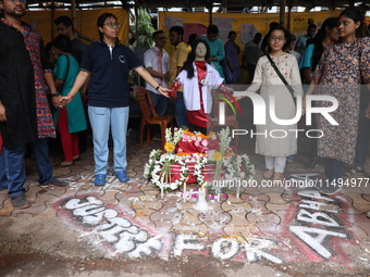 Medical students and doctors are making a human chain with a clay model of a female doctor, a replica of a victim of rape and murder, at R G...