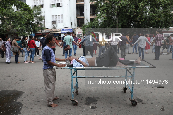 A patient is on a trolley while medical students and doctors are making a human chain during a protest at National Medical College & Hospita...