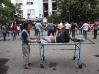 A patient is on a trolley while medical students and doctors are making a human chain during a protest at National Medical College & Hospita...