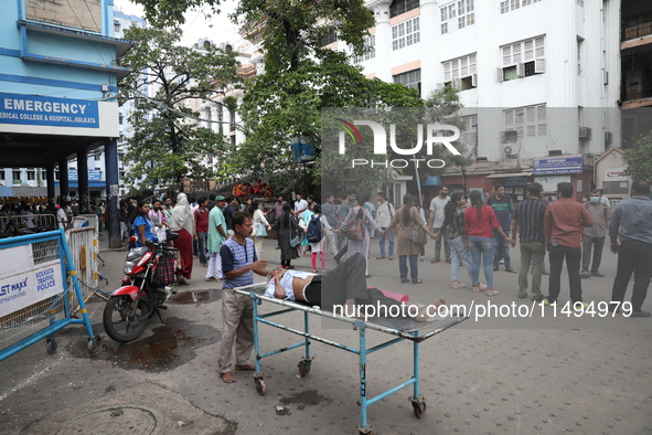 A patient is on a trolley while medical students and doctors are making a human chain during a protest at National Medical College & Hospita...