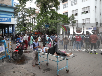 A patient is on a trolley while medical students and doctors are making a human chain during a protest at National Medical College & Hospita...