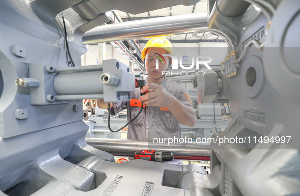 A worker is producing injection molding machines for export at a workshop in Huzhou, Zhejiang province, China, on August 20, 2024. 