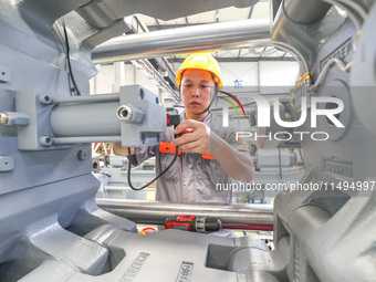 A worker is producing injection molding machines for export at a workshop in Huzhou, Zhejiang province, China, on August 20, 2024. (