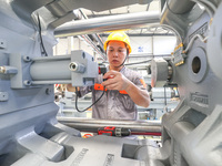 A worker is producing injection molding machines for export at a workshop in Huzhou, Zhejiang province, China, on August 20, 2024. (