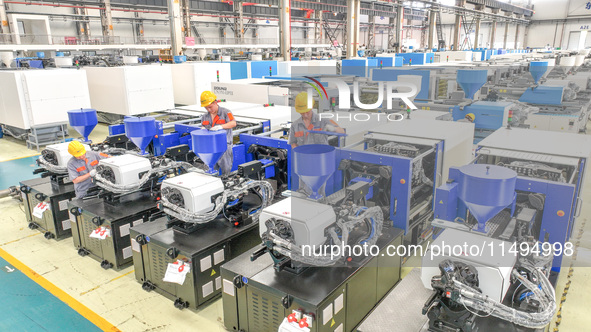 Workers are producing injection molding machines for export at a workshop in Huzhou, Zhejiang province, China, on August 20, 2024. 