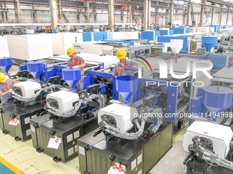 Workers are producing injection molding machines for export at a workshop in Huzhou, Zhejiang province, China, on August 20, 2024. (