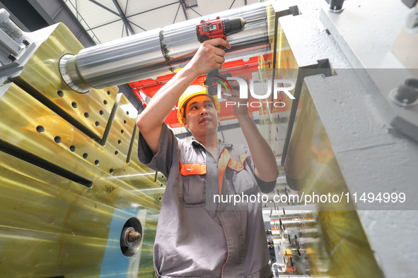 A worker is producing injection molding machines for export at a workshop in Huzhou, Zhejiang province, China, on August 20, 2024. 