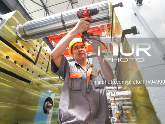 A worker is producing injection molding machines for export at a workshop in Huzhou, Zhejiang province, China, on August 20, 2024. (