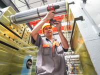 A worker is producing injection molding machines for export at a workshop in Huzhou, Zhejiang province, China, on August 20, 2024. (