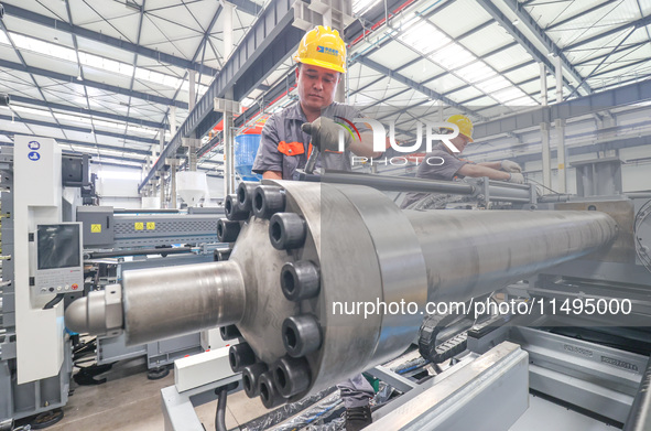 A worker is producing injection molding machines for export at a workshop in Huzhou, Zhejiang province, China, on August 20, 2024. 