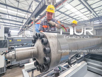 A worker is producing injection molding machines for export at a workshop in Huzhou, Zhejiang province, China, on August 20, 2024. (