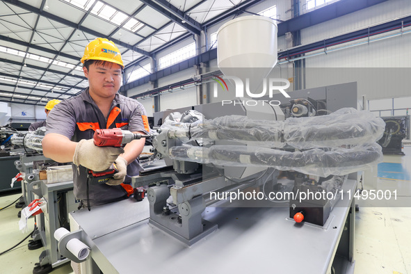 A worker is producing injection molding machines for export at a workshop in Huzhou, Zhejiang province, China, on August 20, 2024. 