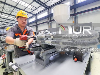 A worker is producing injection molding machines for export at a workshop in Huzhou, Zhejiang province, China, on August 20, 2024. (