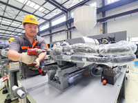 A worker is producing injection molding machines for export at a workshop in Huzhou, Zhejiang province, China, on August 20, 2024. (