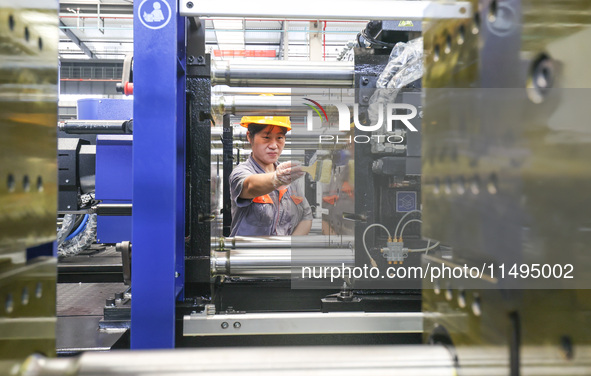 A worker is producing injection molding machines for export at a workshop in Huzhou, Zhejiang province, China, on August 20, 2024. 