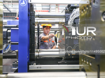 A worker is producing injection molding machines for export at a workshop in Huzhou, Zhejiang province, China, on August 20, 2024. (