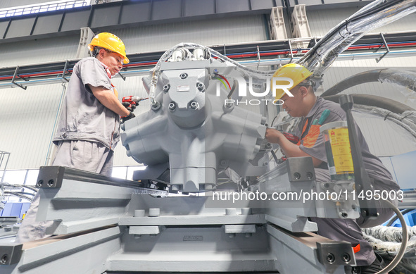 Workers are producing injection molding machines for export at a workshop in Huzhou, Zhejiang province, China, on August 20, 2024. 