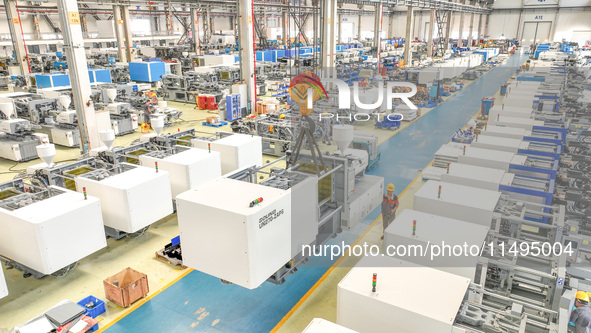 Workers are producing injection molding machines for export at a workshop in Huzhou, Zhejiang province, China, on August 20, 2024. 