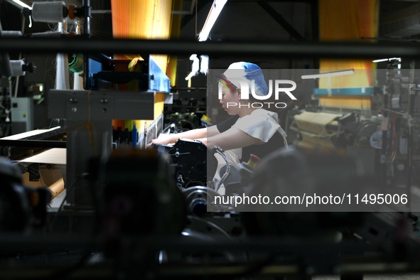 A female textile worker is working at a jacquard loom workshop at Jiangsu Hengyuan Silk Group located in the high-tech zone in Hai 'an, Jian...