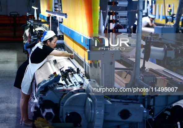 A female textile worker is working at a jacquard loom workshop at Jiangsu Hengyuan Silk Group located in the high-tech zone in Hai 'an, Jian...