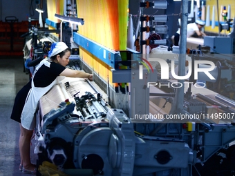 A female textile worker is working at a jacquard loom workshop at Jiangsu Hengyuan Silk Group located in the high-tech zone in Hai 'an, Jian...