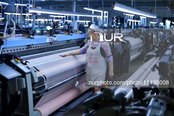 A female textile worker is working at a jacquard loom workshop at Jiangsu Hengyuan Silk Group located in the high-tech zone in Hai 'an, Jian...