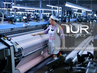 A female textile worker is working at a jacquard loom workshop at Jiangsu Hengyuan Silk Group located in the high-tech zone in Hai 'an, Jian...