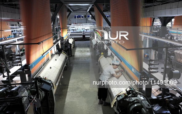 A female textile worker is working at a jacquard loom workshop at Jiangsu Hengyuan Silk Group located in the high-tech zone in Hai 'an, Jian...