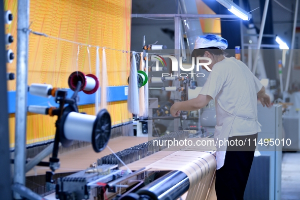 A female textile worker is working at a jacquard loom workshop at Jiangsu Hengyuan Silk Group located in the high-tech zone in Hai 'an, Jian...