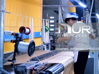 A female textile worker is working at a jacquard loom workshop at Jiangsu Hengyuan Silk Group located in the high-tech zone in Hai 'an, Jian...