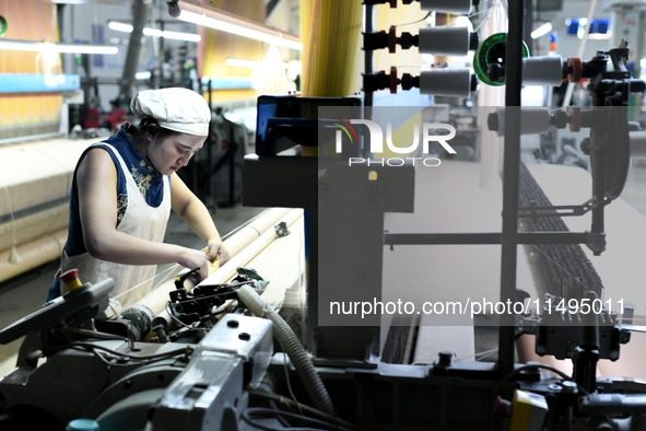 A female textile worker is working at a jacquard loom workshop at Jiangsu Hengyuan Silk Group located in the high-tech zone in Hai 'an, Jian...