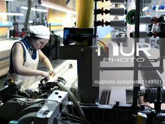 A female textile worker is working at a jacquard loom workshop at Jiangsu Hengyuan Silk Group located in the high-tech zone in Hai 'an, Jian...