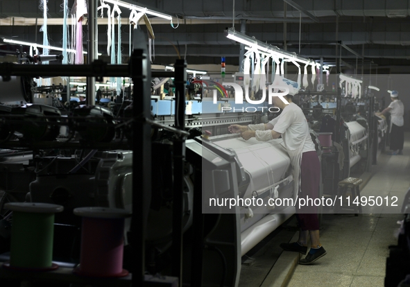 A female textile worker is working at a jacquard loom workshop at Jiangsu Hengyuan Silk Group located in the high-tech zone in Hai 'an, Jian...