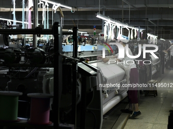 A female textile worker is working at a jacquard loom workshop at Jiangsu Hengyuan Silk Group located in the high-tech zone in Hai 'an, Jian...