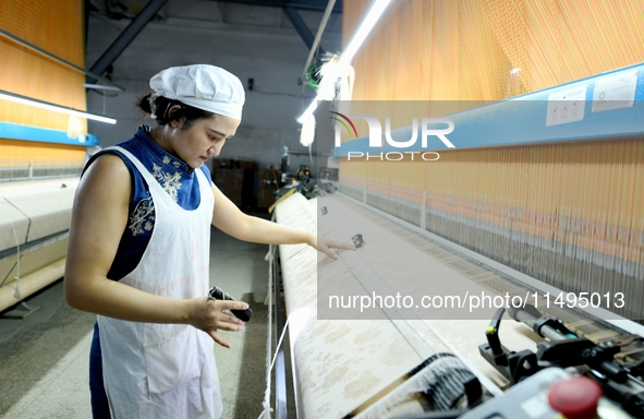 A female textile worker is working at a jacquard loom workshop at Jiangsu Hengyuan Silk Group located in the high-tech zone in Hai 'an, Jian...