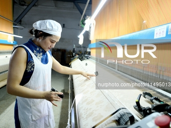 A female textile worker is working at a jacquard loom workshop at Jiangsu Hengyuan Silk Group located in the high-tech zone in Hai 'an, Jian...